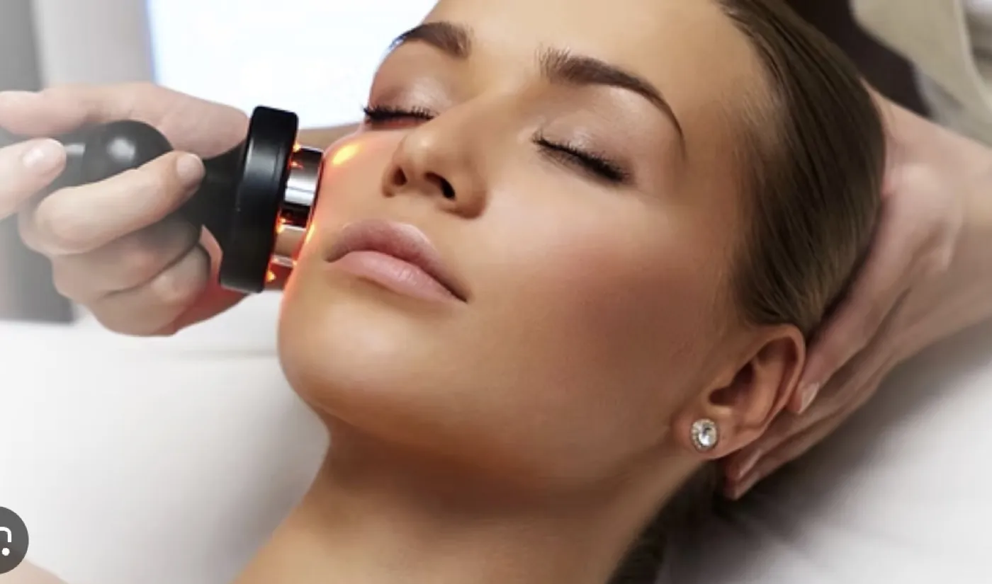 An aesthetician using a radiofrequency device on a client’s cheek
