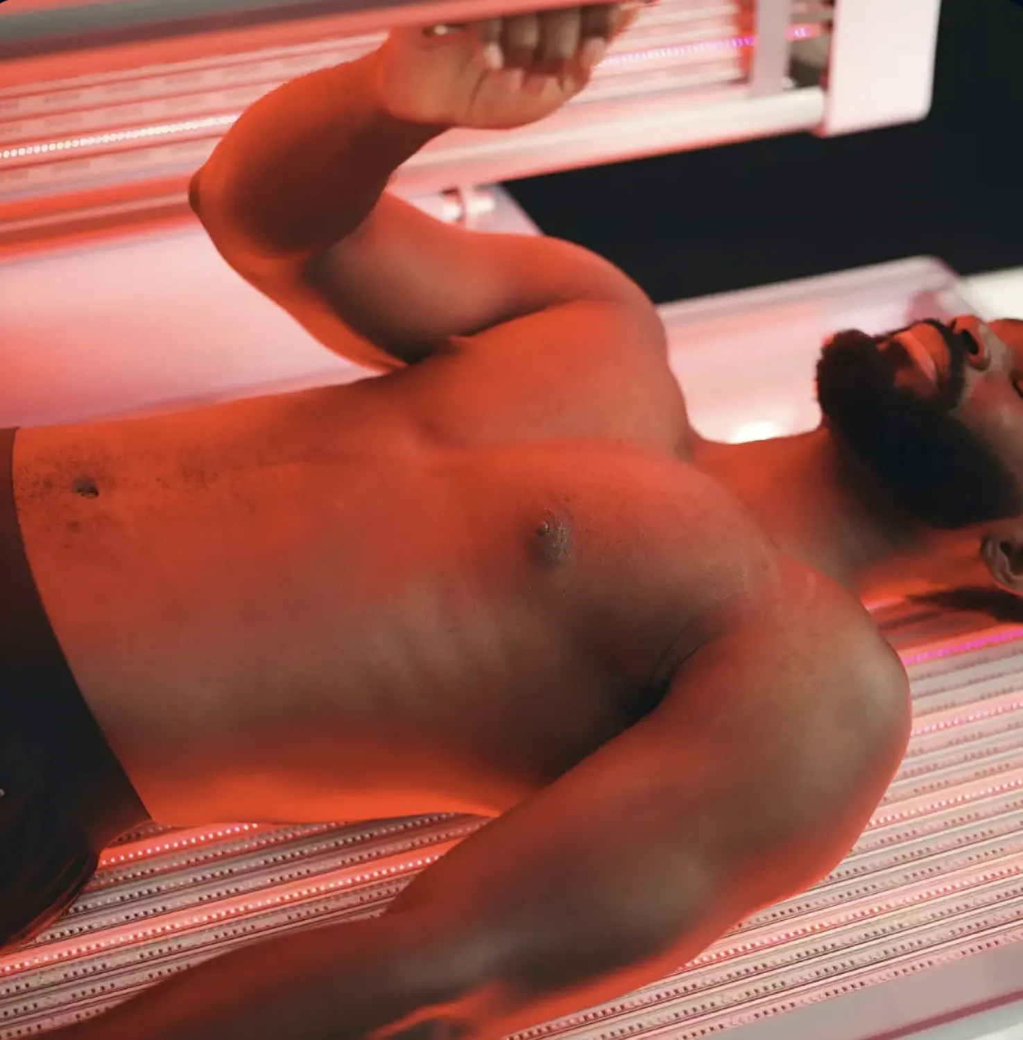 A man lying in a full-body red light therapy bed